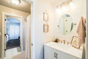 Bathroom with curtained shower, vanity, and ceiling fan