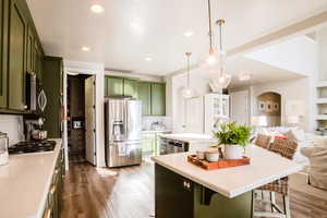 Kitchen with stainless steel appliances, green cabinets, tasteful backsplash, and pendant lighting