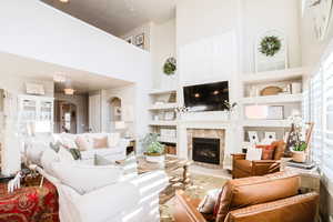 Living room featuring a high ceiling, a high end fireplace, built in shelves, and hardwood / wood-style flooring