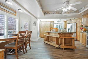 Kitchen featuring dark wood-type flooring, a raised ceiling, ceiling fan, tasteful backsplash, and stainless steel appliances