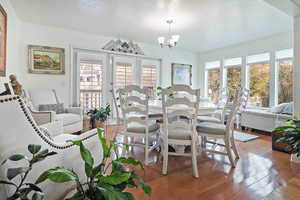 Dining area featuring a wealth of natural light, wood-type flooring, and an inviting chandelier