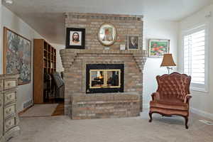 Living area featuring a fireplace, carpet floors, and a textured ceiling