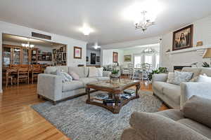 Living room with hardwood / wood-style flooring, a brick fireplace, ornamental molding, and brick wall