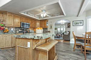 Kitchen with decorative backsplash, a kitchen island, stainless steel appliances, and ceiling fan with notable chandelier