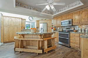 Kitchen featuring a kitchen bar, a kitchen island, dark wood-type flooring, and appliances with stainless steel finishes