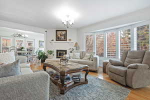 Living room with crown molding, light wood-type flooring, a fireplace, and a chandelier