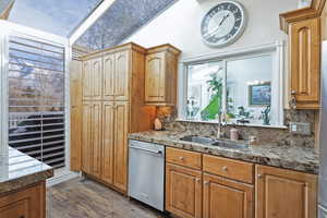 Kitchen with light stone countertops, sink, tasteful backsplash, dark hardwood / wood-style flooring, and stainless steel dishwasher