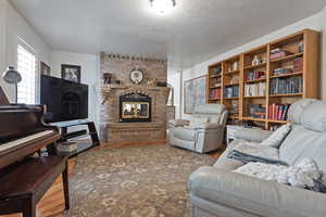 Living room featuring a textured ceiling, wood-type flooring, and a fireplace