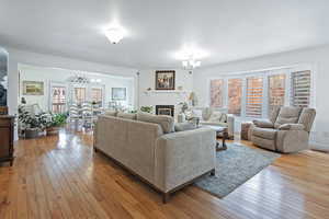 Living room featuring a notable chandelier, ornamental molding, a fireplace, and light hardwood / wood-style flooring