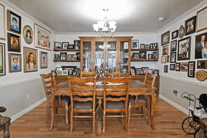 Dining space featuring light wood-type flooring, an inviting chandelier, and ornamental molding