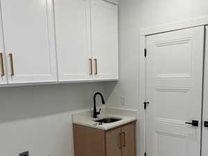 Clothes washing area featuring sink, cabinets, and hookup for an electric dryer