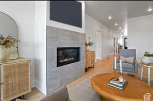 Living room with a tiled fireplace and light hardwood / wood-style flooring