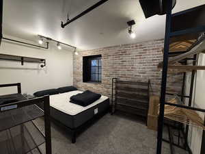 Carpeted bedroom with brick wall and track lighting