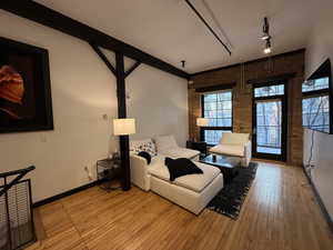 Living room featuring light hardwood / wood-style floors, brick wall, and rail lighting