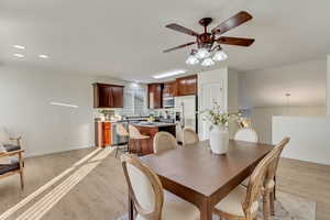 Dining space with ceiling fan and light wood-type flooring