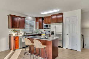 Kitchen featuring sink, a center island, a kitchen bar, light wood-type flooring, and appliances with stainless steel finishes