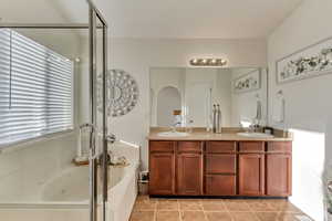 Bathroom with vanity, shower with separate bathtub, tile patterned flooring, and a wealth of natural light