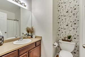 Bathroom with toilet, vanity, and curtained shower