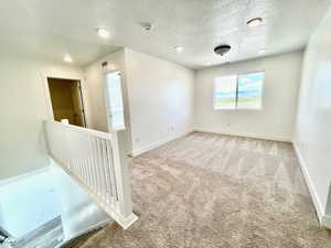 Carpeted empty room featuring a textured ceiling