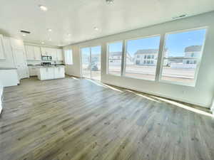 Unfurnished living room with sink, a textured ceiling, plenty of natural light, and light hardwood / wood-style flooring