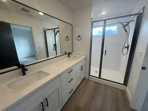 Bathroom with hardwood / wood-style flooring, vanity, and an enclosed shower