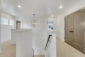 Hallway featuring a notable chandelier and light carpet