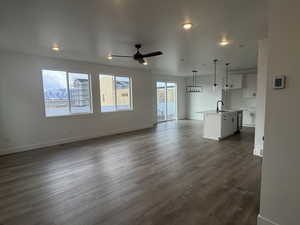 Unfurnished living room featuring dark wood-type flooring, sink, and ceiling fan