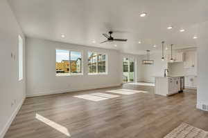 Unfurnished living room with recessed lighting, light wood-style floors, baseboards, and a ceiling fan