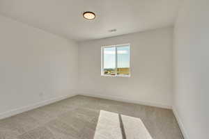Empty room featuring light colored carpet, baseboards, and visible vents