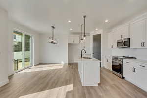 Kitchen with light wood-style flooring, appliances with stainless steel finishes, a sink, and a wealth of natural light