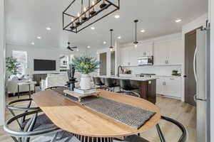 Dining space featuring light hardwood / wood-style floors, sink, and ceiling fan with notable chandelier