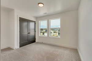 Unfurnished bedroom with a closet, baseboards, carpet, and visible vents