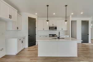 Kitchen with a sink, light countertops, light wood finished floors, and stainless steel appliances