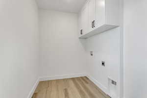 Laundry room featuring washer hookup, light hardwood / wood-style floors, cabinets, and electric dryer hookup