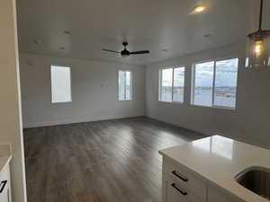 Unfurnished living room with ceiling fan, dark hardwood / wood-style flooring, and sink