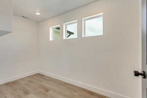 Empty room with visible vents, baseboards, light wood-type flooring, and recessed lighting