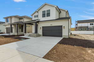View of front of house featuring board and batten siding, an attached garage, covered porch, and concrete driveway