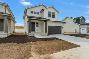 View of front of house with concrete driveway, board and batten siding, an attached garage, and covered porch