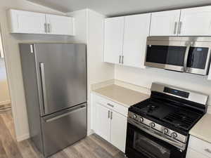 Kitchen with appliances with stainless steel finishes, white cabinetry, and light hardwood / wood-style floors