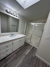 Bathroom with walk in shower, a skylight, vanity, and hardwood / wood-style flooring