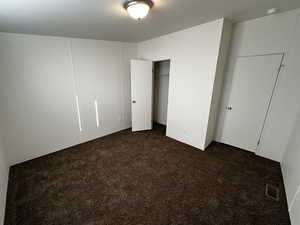 Unfurnished bedroom with dark carpet