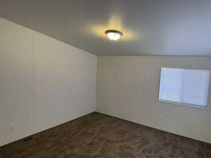 Spare room featuring dark colored carpet