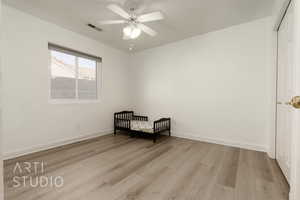 Unfurnished bedroom with a nursery area, a closet, ceiling fan, and light hardwood / wood-style floors