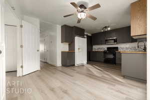 Kitchen featuring sink, light wood-type flooring, black gas stove, wood counters, and white refrigerator with ice dispenser