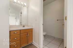 Bathroom with toilet, tile patterned floors, and vanity