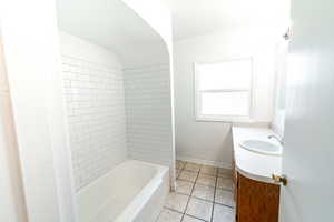 Bathroom with vanity, tile patterned floors, and tiled shower / bath