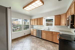 Kitchen featuring tasteful backsplash, sink, light tile patterned flooring, stainless steel appliances, and light stone counters