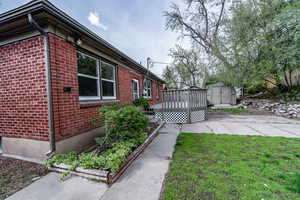 View of property exterior with a wooden deck and a storage unit