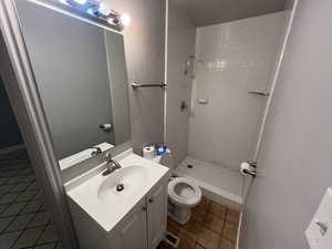 Bathroom featuring walk in shower, tile patterned flooring, vanity, and toilet