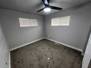 Unfurnished room with dark carpet, ceiling fan, and crown molding